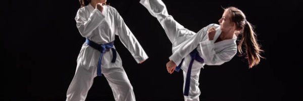 Two girls in taekwondo combat practicing martial arts. They wears kimonos