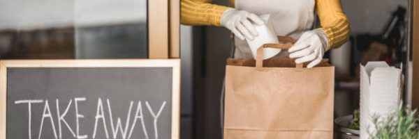 Young woman preparing takeaway healthy food inside restaurant during Coronavirus outbreak time - Worker inside kitchen cooking vegetarian food for online order service - Focus on salad