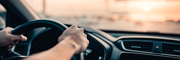 Close-up - Hand of man driving car on the road.