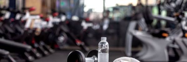 Dumbbell, water bottle, towel on the bench in the gym.