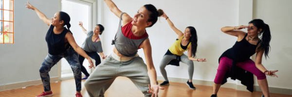 Group of energetic hip-hop dancers focused on training while gathered together in spacious dance hall