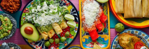 Green and red enchiladas with mexican sauces mix in colorful table